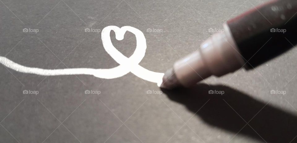 a silvery inky marker drawing a love heart