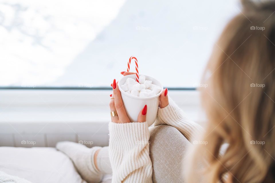 Beautiful woman with cup of hot drink at home in winter season 