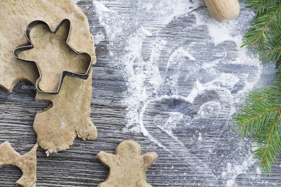 Christmas, gingerbread cookies on a wooden table sprinkled with flour, with tangerines and a green Christmas tree.