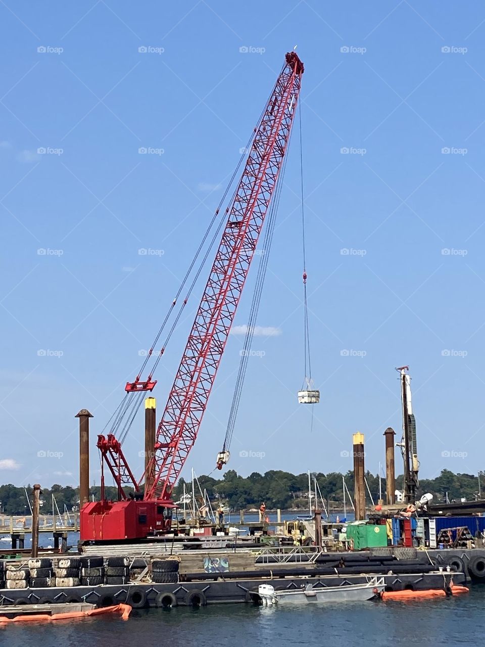 Red crane hauling material on water