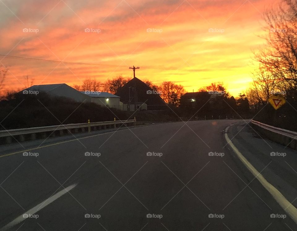 A beautiful sunset on a crisp, autumn day with tall trees in the distance with clouds passing through the sky.