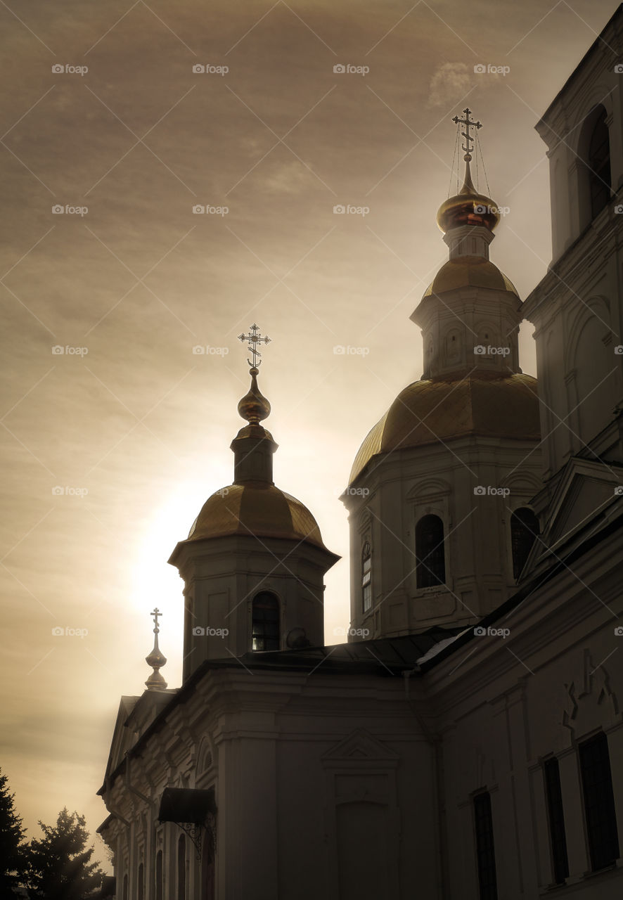 Silhouettes of the domes of the Kazan Cathedral of Holy Trinity Seraphim-Diveevsky monastery (Diveevo, Russia) in the rays of the rising sun on a sunny spring morning against the cloudy sky