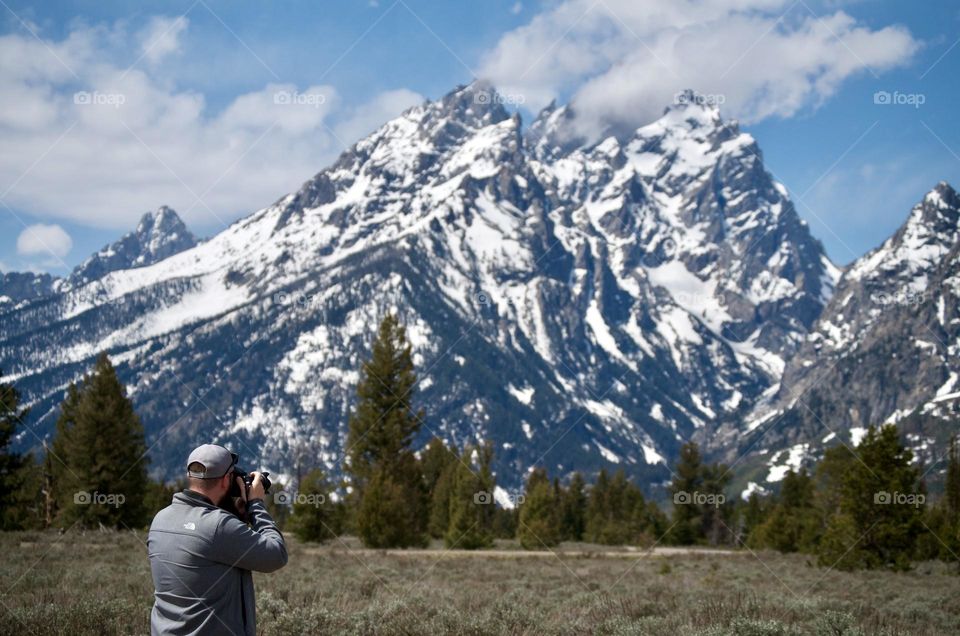 A man take photos of the Grand Teton mountain range