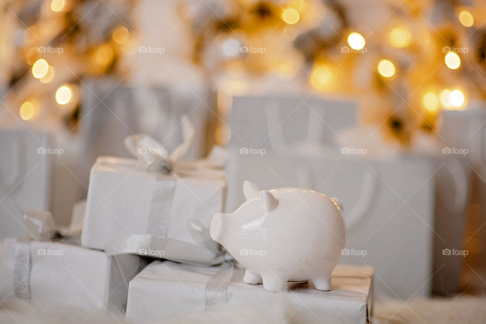 piggy bank with 100 dollars banknote in festive New Year atmosphere of scenery. Magical bokeh with Christmas tree and bright lights.