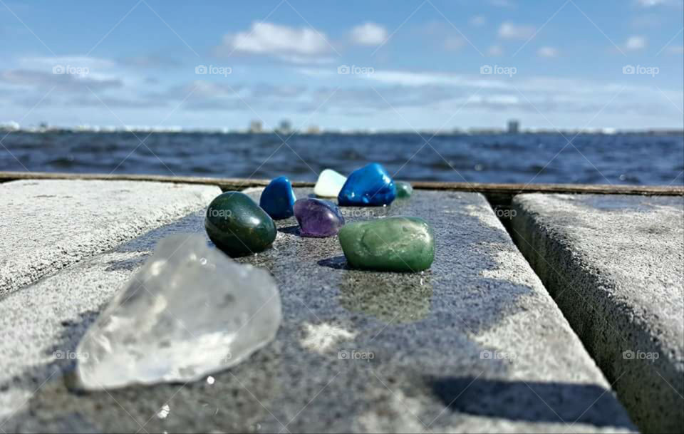 Different colored stones on a dock over looking an island in the distance