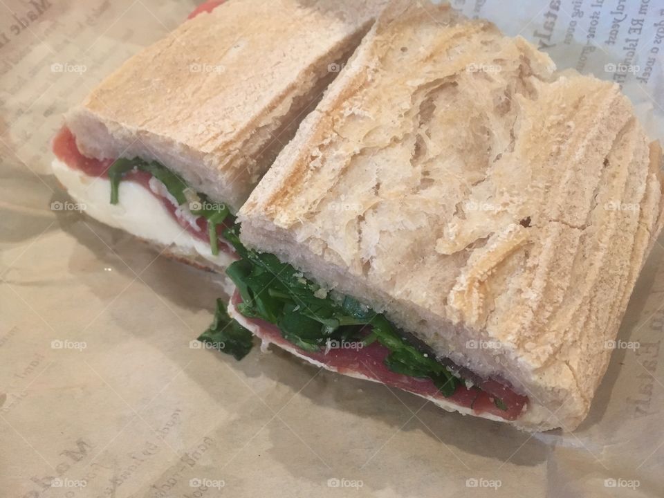 A sandwich from an Italian deli with white bread, prosciutto, mozzarella and tomato 