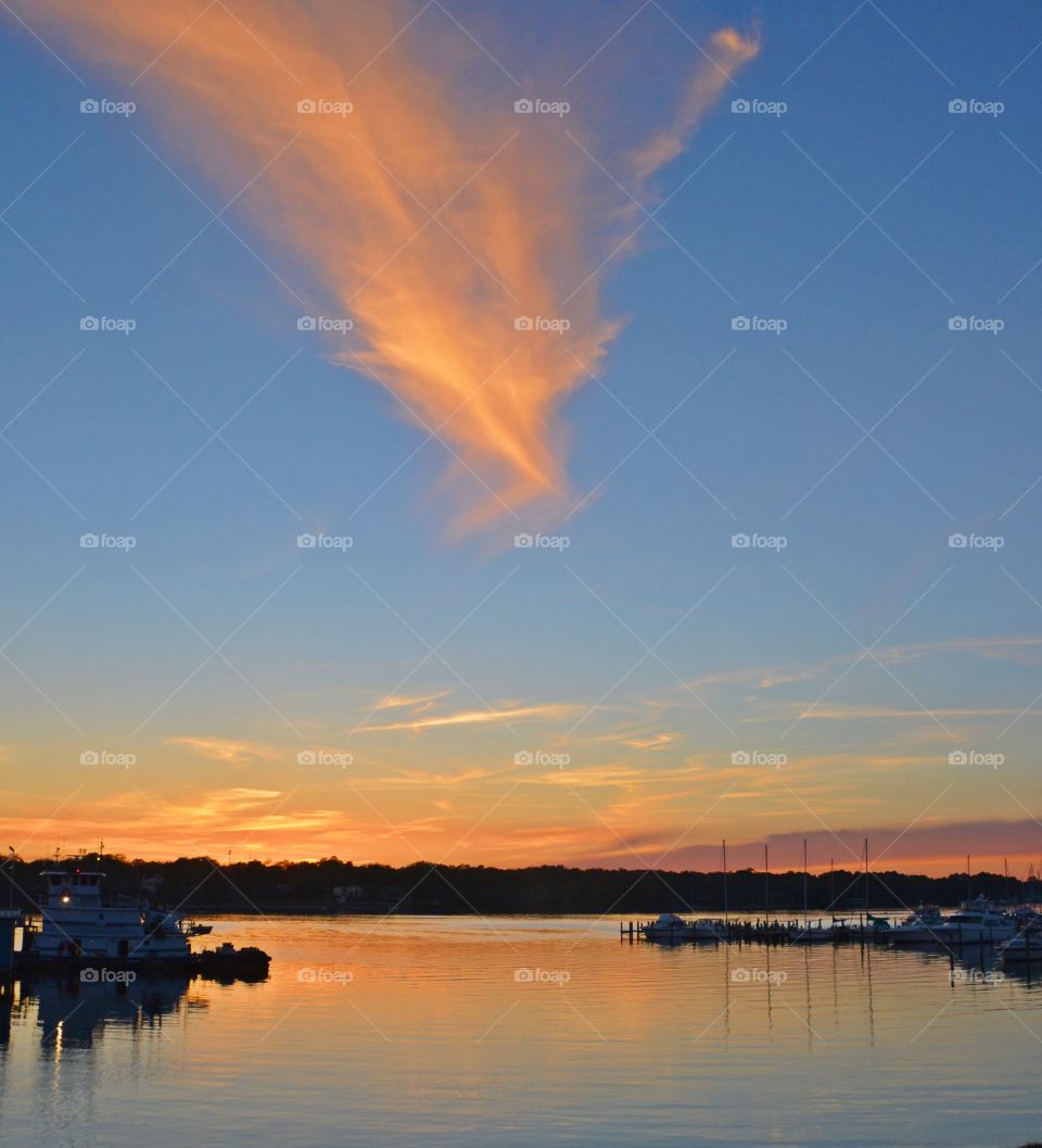 Orange Glaze - a magnificent sunset colors the surface of the bay as well as reflecting of the wispy clouds as the sailboats sit silent