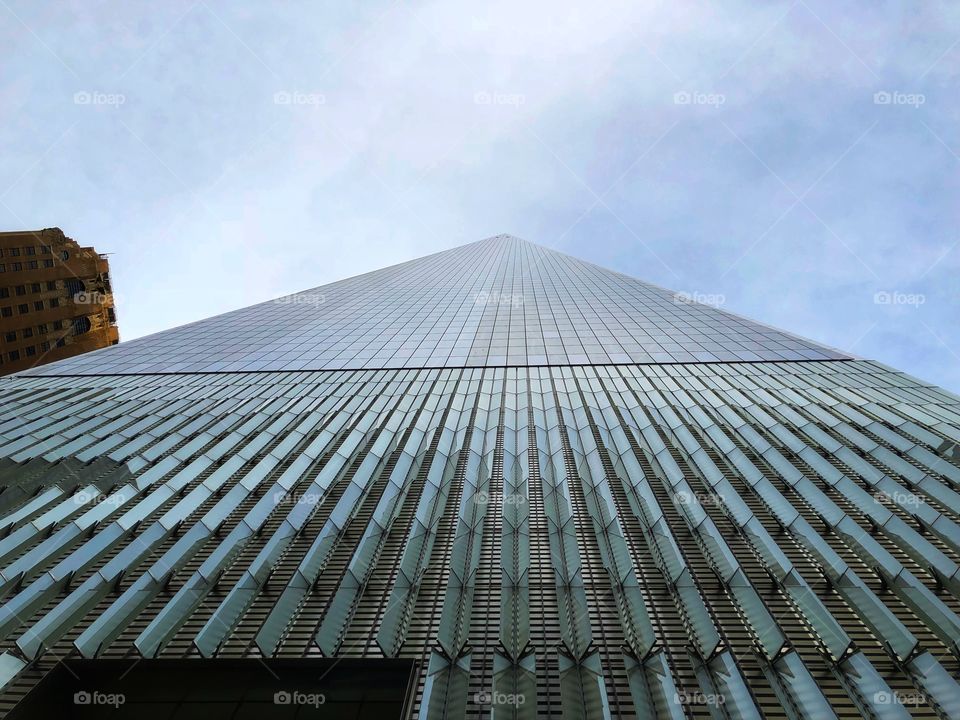 Looking up to the One World Trade Center, in a cloudy day. The better example of “looking to the infinite”. Majestic and Impressive.