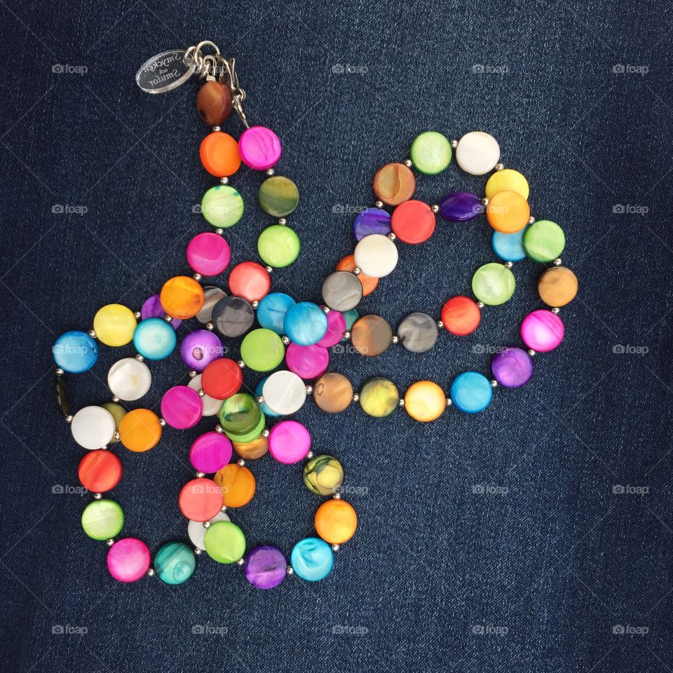 Multicolored necklace on blue jeans background 