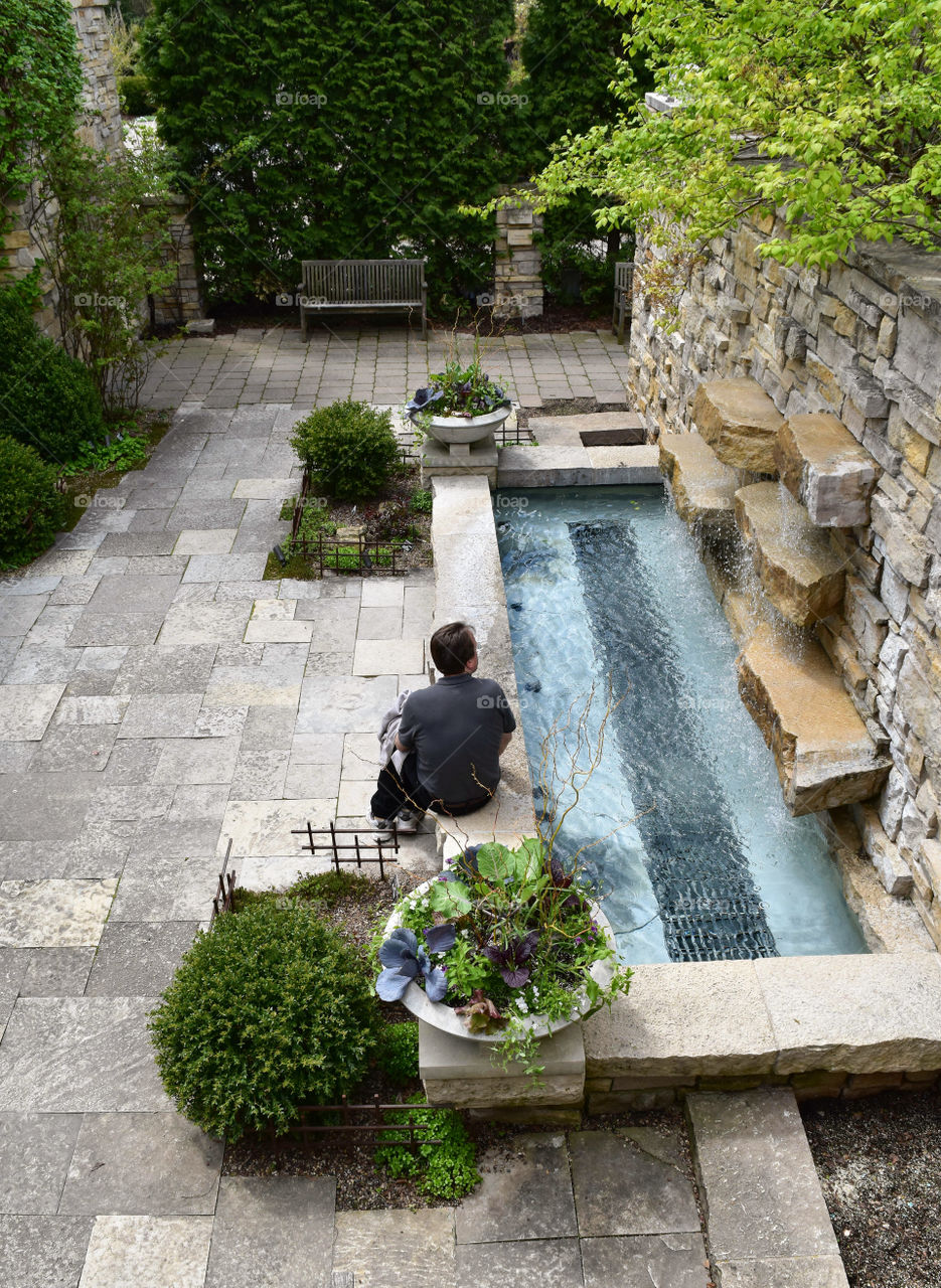 Man meditating by a reflection pool in a peaceful garden