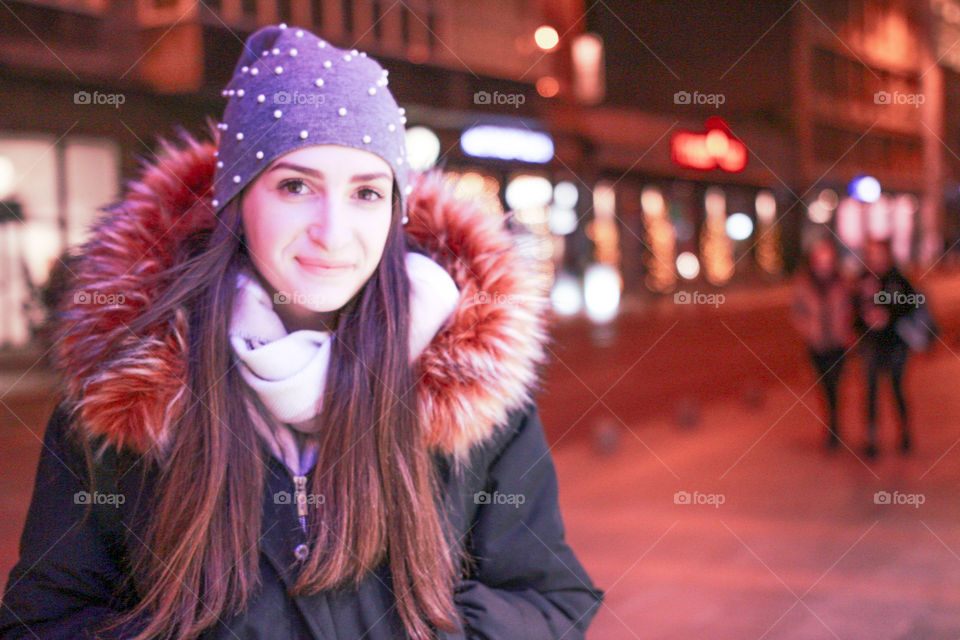 Night portrait of a young woman with a bokeh in the background