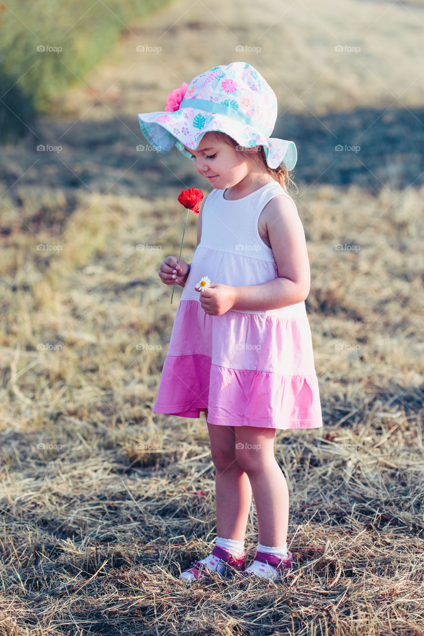 Lovely little girl in the field of wild flowers. Cute girl picking the spring flowers for her mom for Mother's Day in the meadow. Spending time close to nature