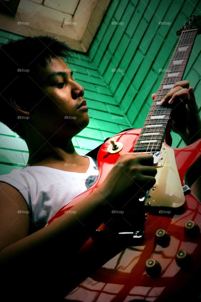 young asian teenager playing an electric guitar