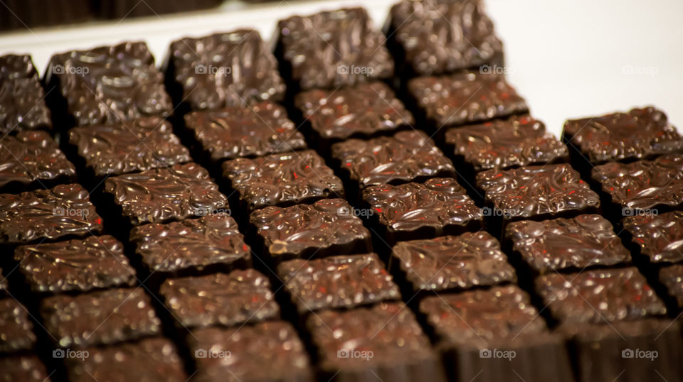 Beautiful gourmet chocolate squares on white porcelain tray Decadent dark chocolate dessert photography background with selective focus