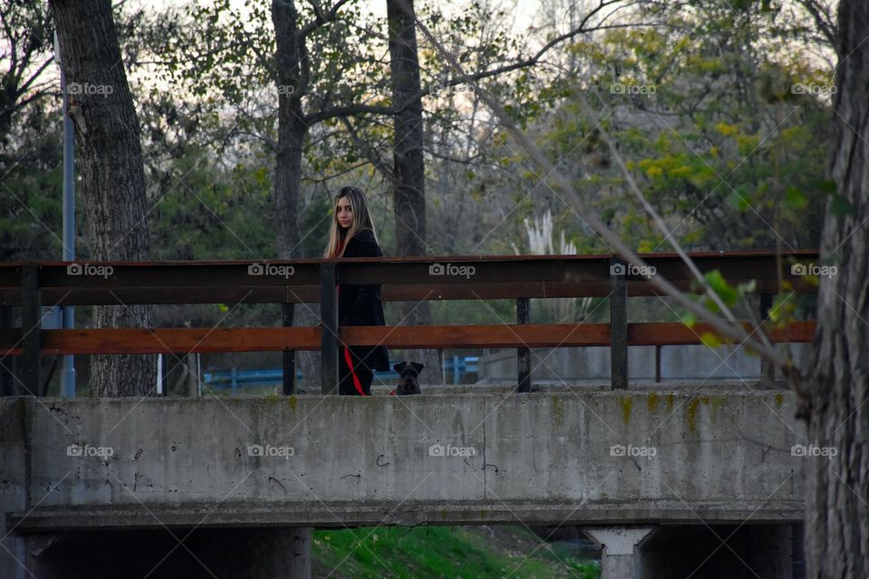 chica paseando al perro en un puente