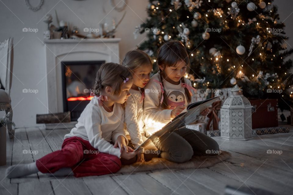 Little sisters near Christmas tree at home