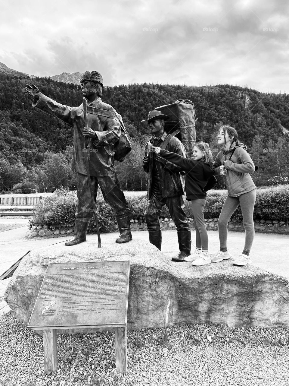 Historical black and white photo of two gold rush explorers in the Klondike with two young girls imitating the men behind.