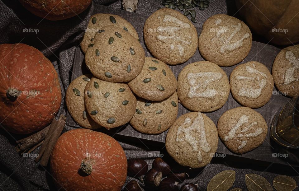 Trick or treat - pumpkin cookies decorated with icing or seeds and surrounded by autumnal ingredients 