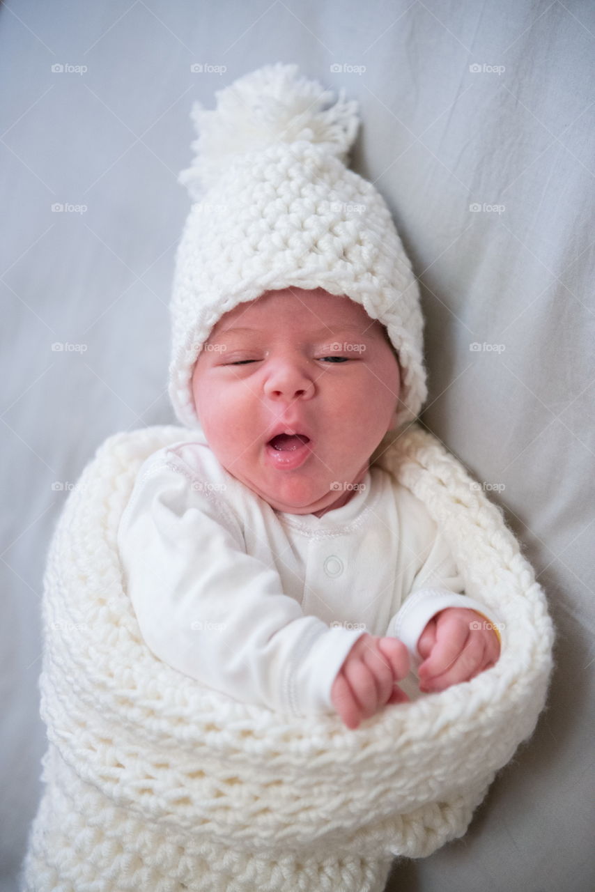 newborn in a cocoon making a funny face wants to sleep