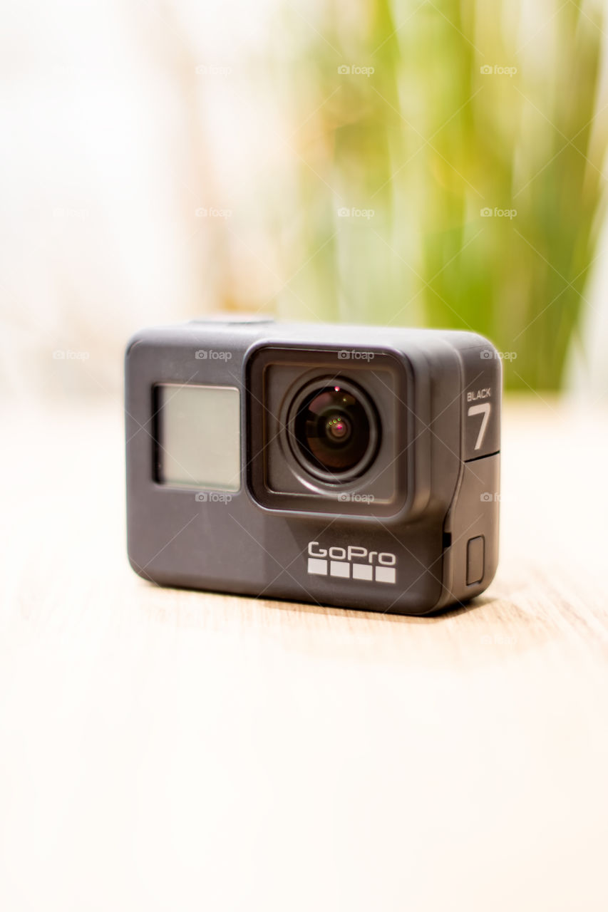 GoPro Hero 7 action camera, sitting on a table isolated from a bright background. 