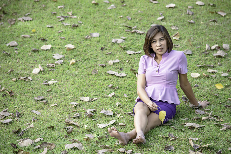 Portrait Asean woman sitting on the lawn in a park.