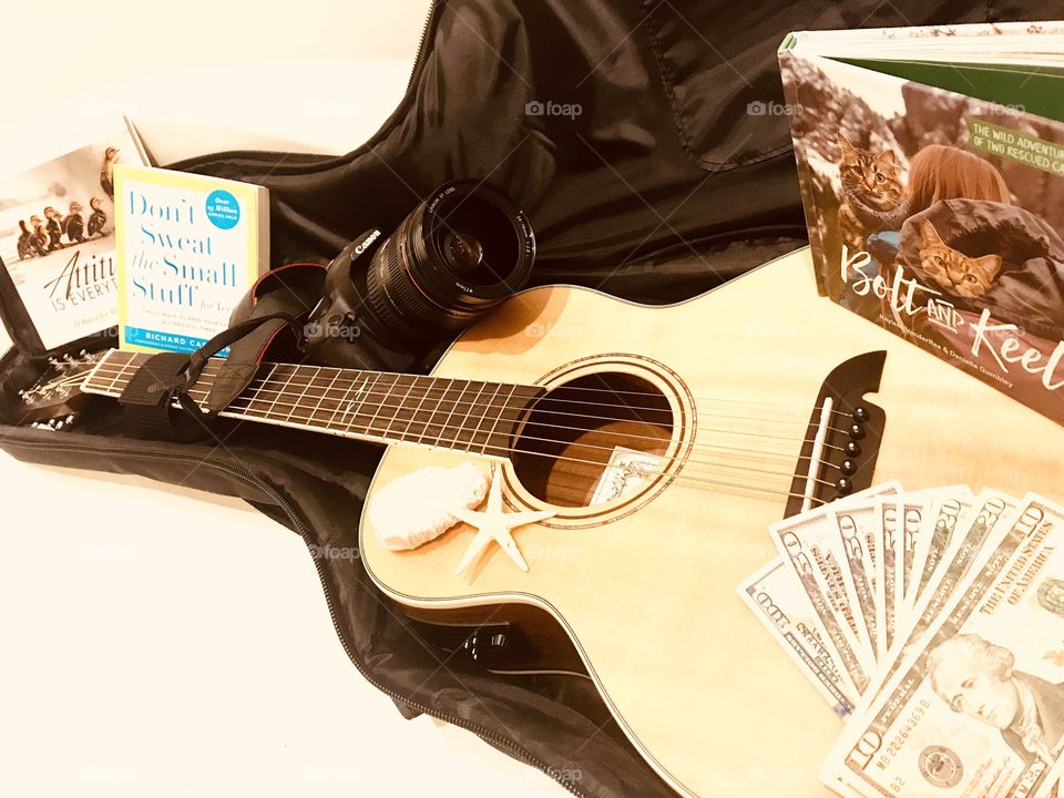 Fun photo of guitar with guitar case filled with books, money, and camera for trip! 