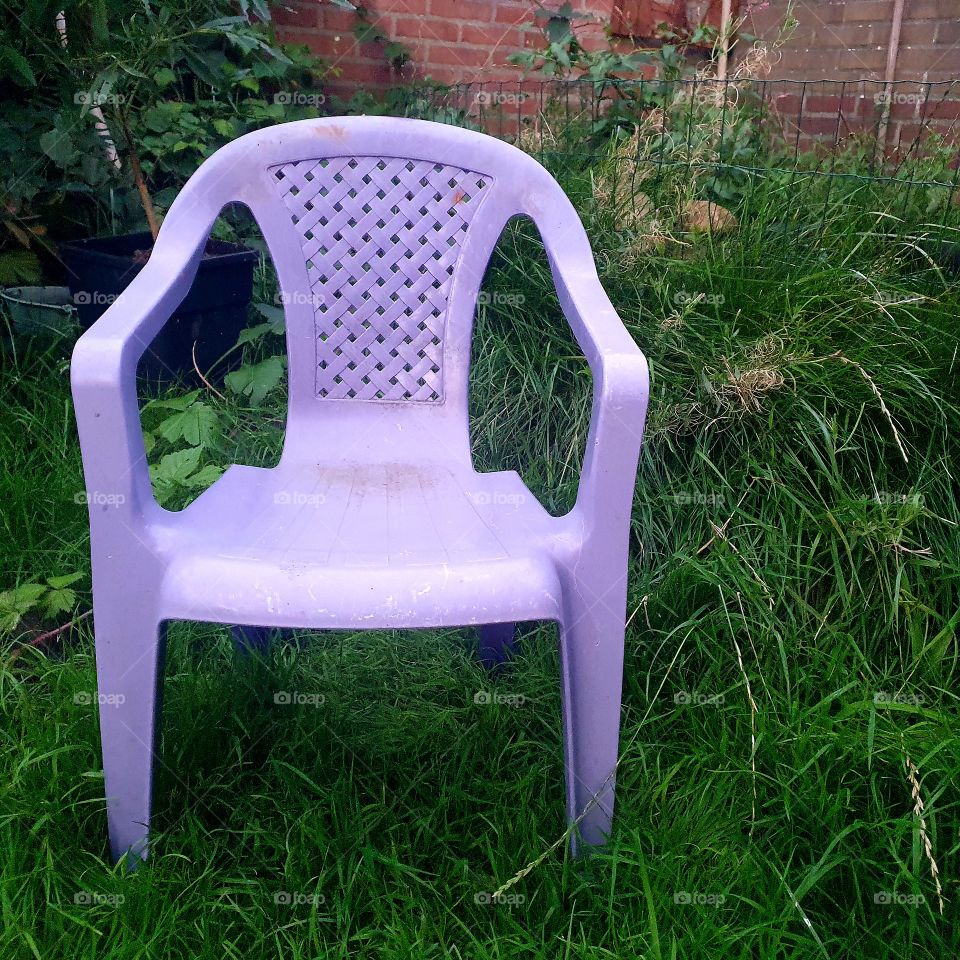 Purple child's seat in the grass next to the pond - backyard the Netherlands