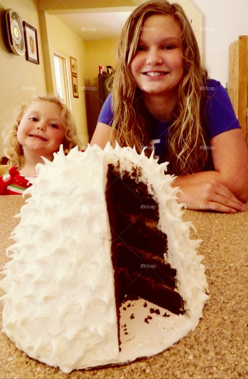 Close-up of cake in front two happy sister