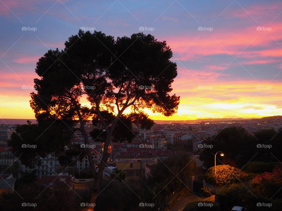 View of colorful sky at sunset overlooking the old town and sea in Nice, France.