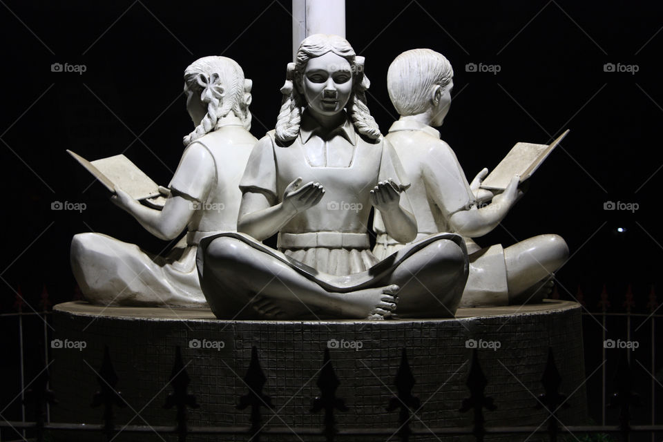 a statue of children reading books and studying.