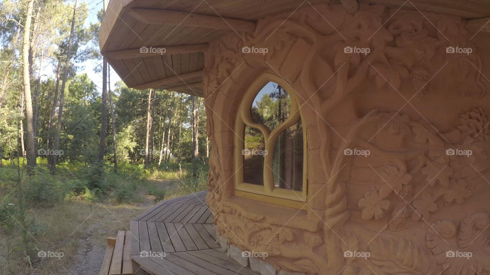 Clay house with decorations on the external wall. Perfectly harmonized in a wild forest