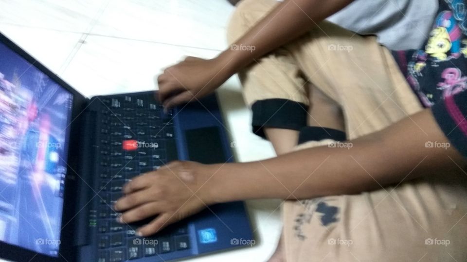 child operating  in laptop playing games