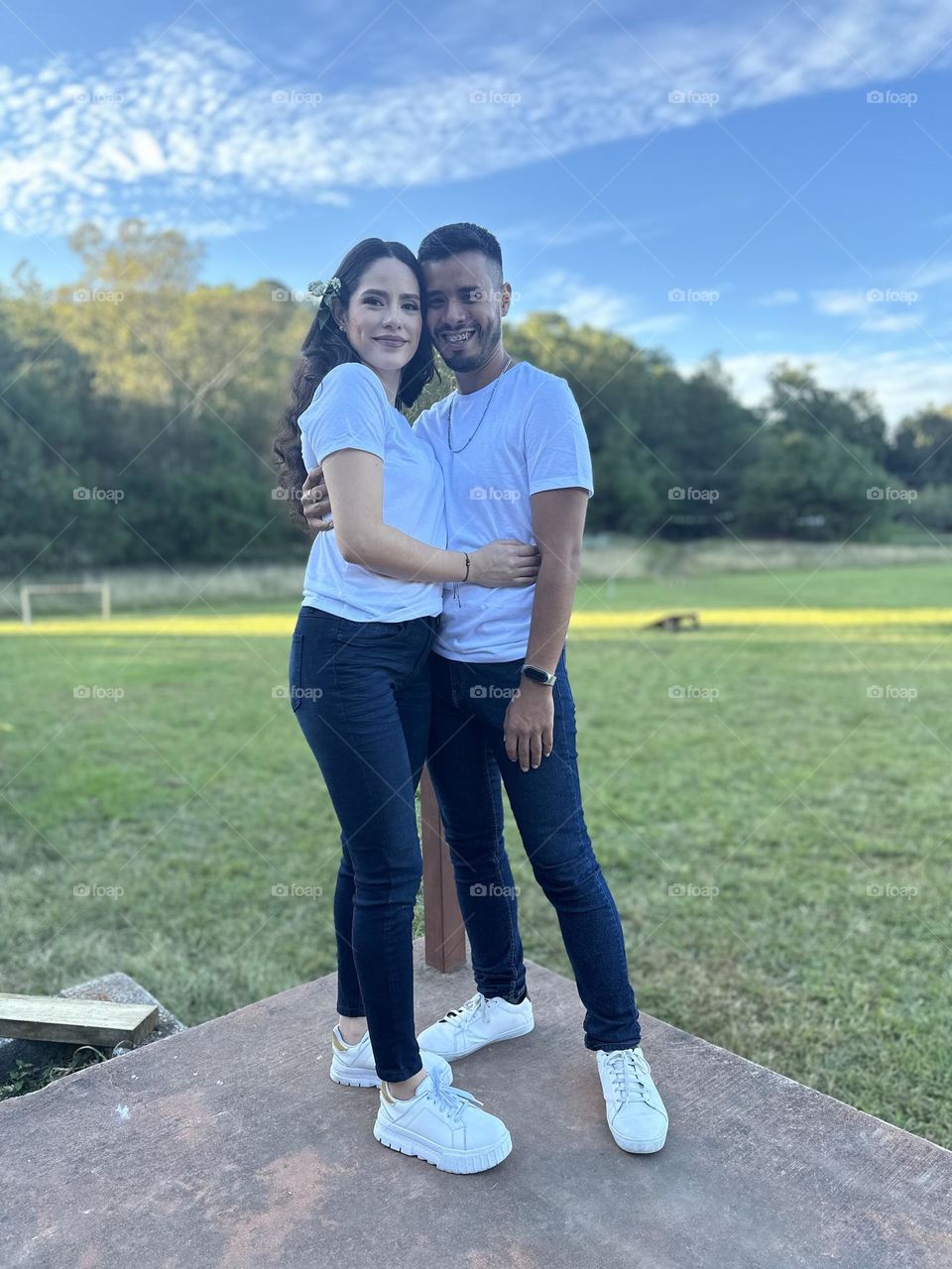 Young couple posing for a portrait on a beautiful and green landscape in a sunny day.