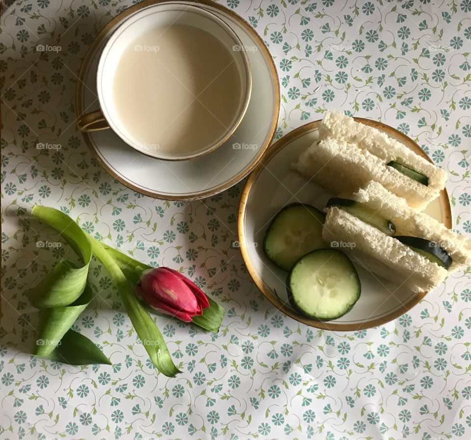 A delicious fresh cucumber sandwich on white bread displayed on a floral background with a teacup and a pink tulip flower. USA, America