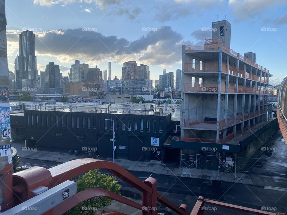 From the top of the stairs of the “Pulaski Bridge” at “Newtown Creek” on the “Greenpoint”, Bklyn side we look across onto a scaffolded construction site and in the distance onto LIC, Queens and “Manhattan”. 2023. Hypnotic Productions
