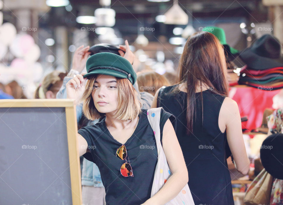 Cute girl is trying on a hat