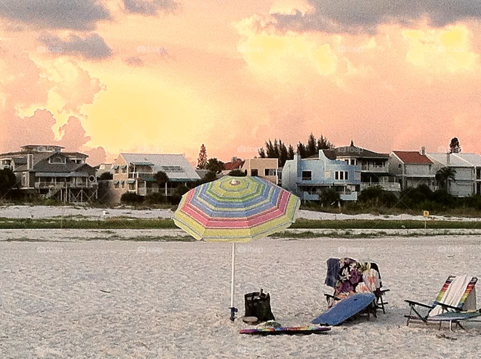 Beach days. Beach chair and umbrella on Siesta Key with colorful beach houses in background.