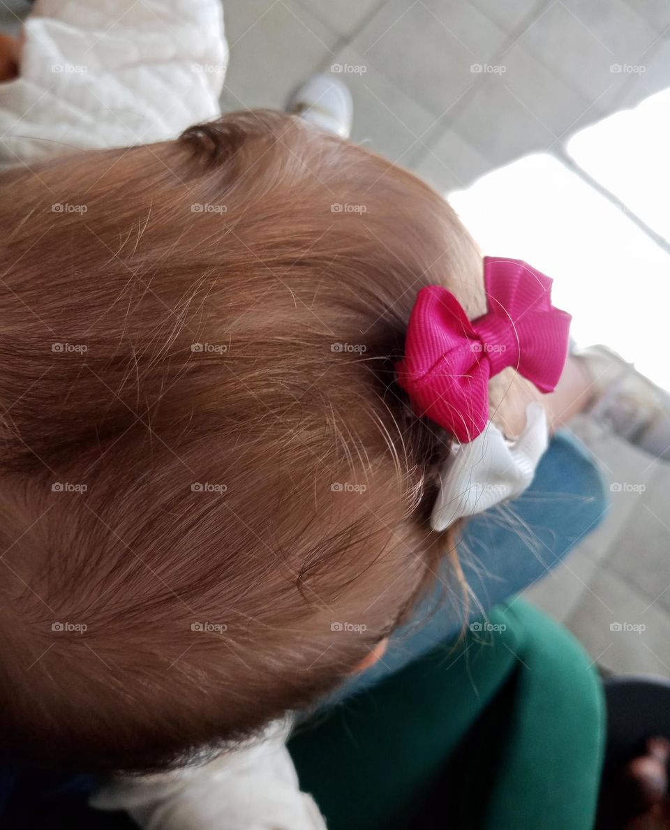 Pink and white bow on a baby girl's hair,  seen from above