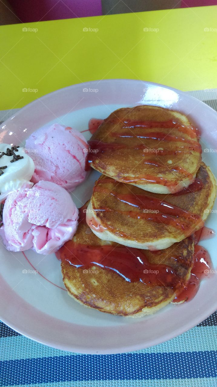 Pancake topping with syrup and strawberry ice-cream.