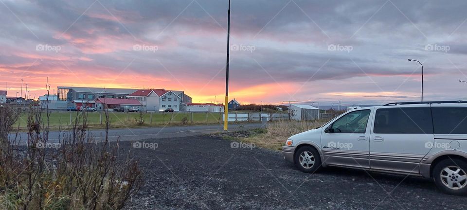 sunset in small town. beautiful red colours highlighting the local school. Family car watching the view.