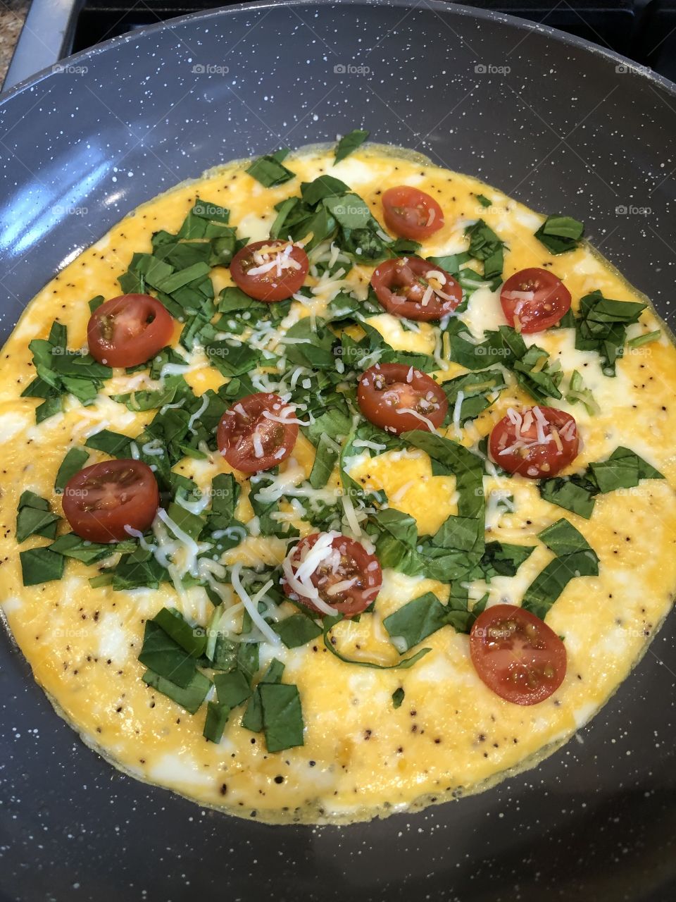 A delicious breakfast omelet with cherry tomatoes, eggs, pepper, spinach, and cheese. This is a great idea for breakfast! 