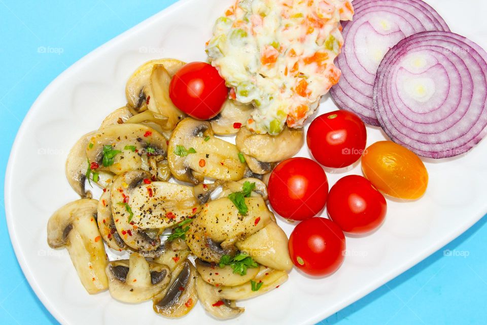 Stewed mushrooms with vegetables on a white plate