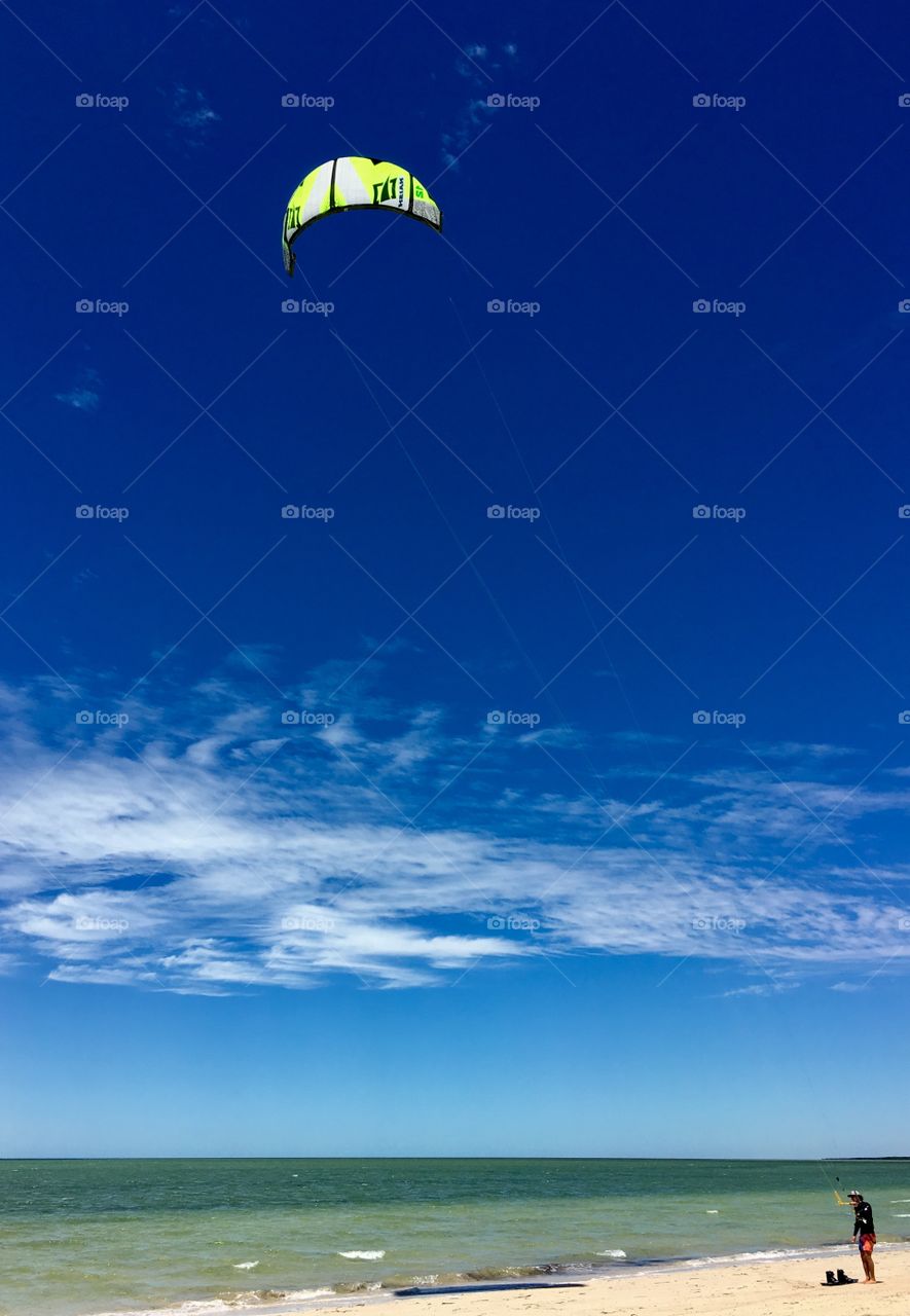 Kite boarder on beach testing out kite before heading out; over ocean on windy day