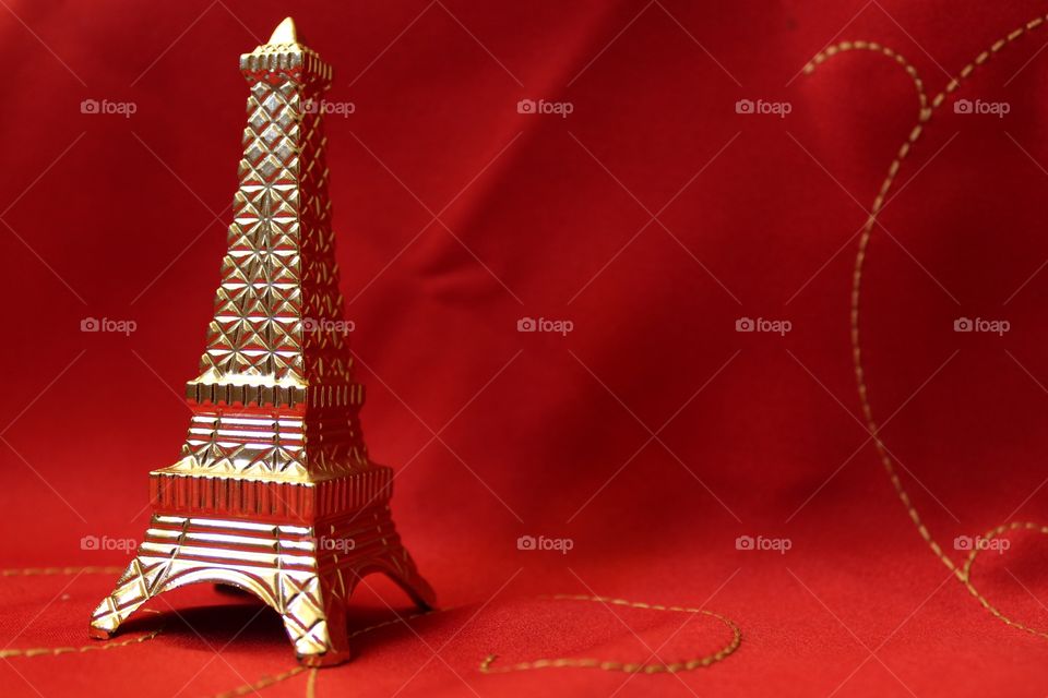 Golden Eiffel tower miniature plastic toy on a red background