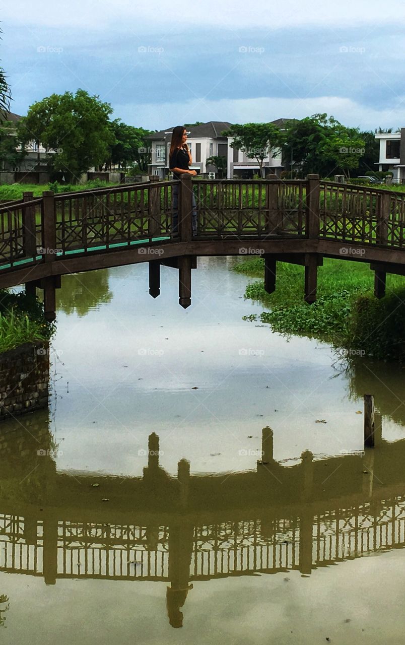 A girl on the small bridge and reflection at the water 