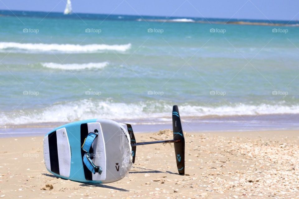 Surfing board on the beach with the blue sea on background 