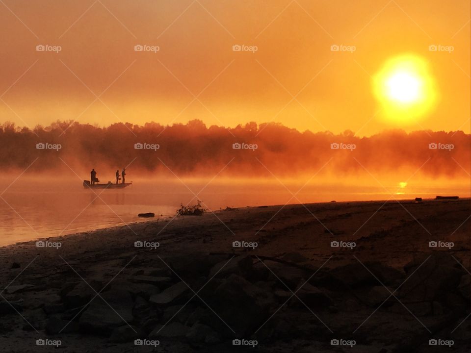 People fishing in lake at sunrise