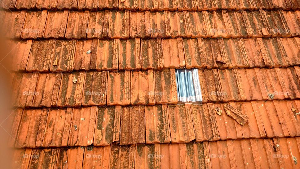 Telhado antigo com uma telha nova transparente em plástico para iluminação natural.