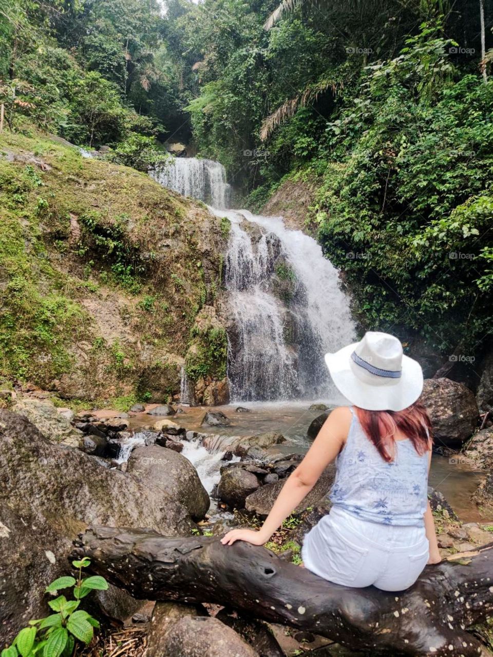 Portrait of woman sitting against waterfall