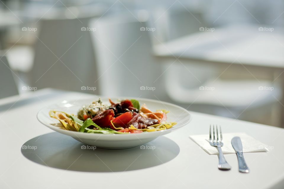 close-up of a young man eating a salad in a light kitchen